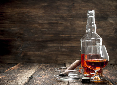 French cognac with a smoking cigar. On a wooden background.の写真素材