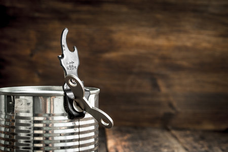 Food in tin can with opener. On a wooden background.の写真素材