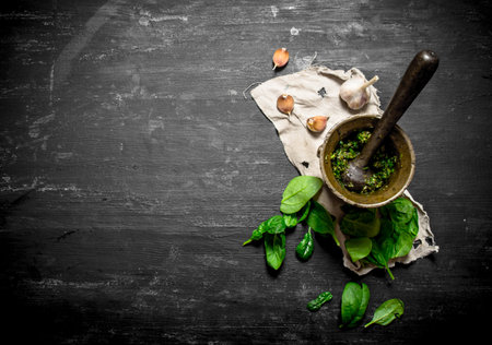 Pesto in a mortar with garlic and olive oil. On the black wooden table.の写真素材