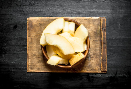 Sliced melon in a wooden bowl . On the black wooden table.の写真素材