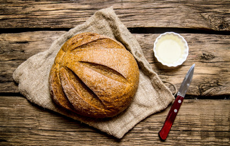 Fresh bread with knife and oil. On the wooden table. Top view