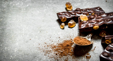 Chocolate with hazelnuts and cocoa powder on the spoon. On the stone table.