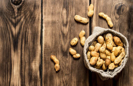 Peanuts in the old bag. On wooden background.