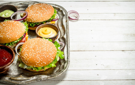 Burgers with beef and vegetables on a steel tray. On a white wooden background.の写真素材