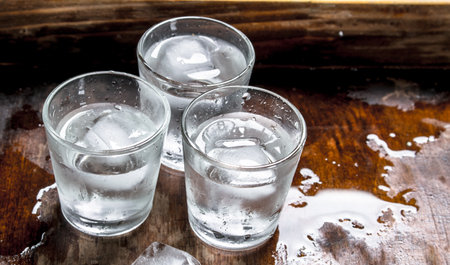 Vodka shots with ice on a wooden table.の写真素材