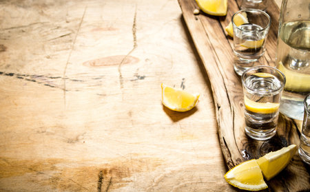Vodka in shot glasses with lemon. On wooden background.の写真素材