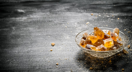 Crystalline cane sugar in a saucer. On black rustic background.の写真素材