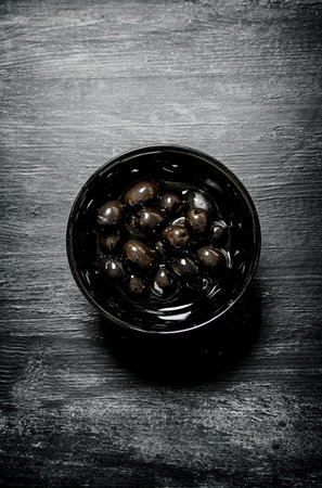 Olives in brine in the pan. On black rustic background.の写真素材