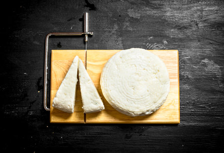 Fresh goat cheese on a cutting Board. On a black wooden background.の写真素材