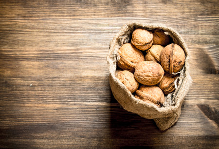 Walnuts in the old sack. On a wooden table.