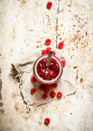 Jam from wild raspberries in the jar. On rustic background .
