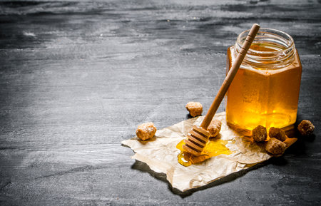 Natural honey with a spoon on old paper. On black rustic table.の写真素材