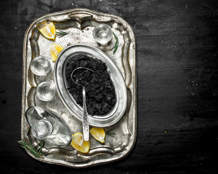 Vodka with caviar on the old tray. On a black chalkboard.の写真素材