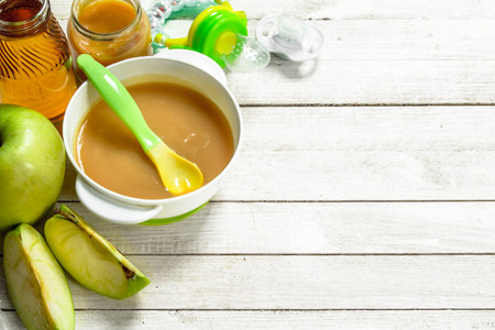 Baby food. Baby puree from fresh green apples. On a white wooden background.の写真素材