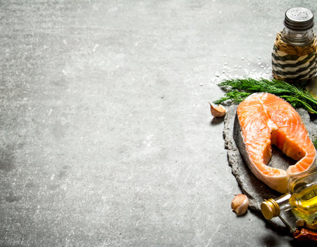 piece of raw salmon with spices and herbs. On a stone background.の写真素材