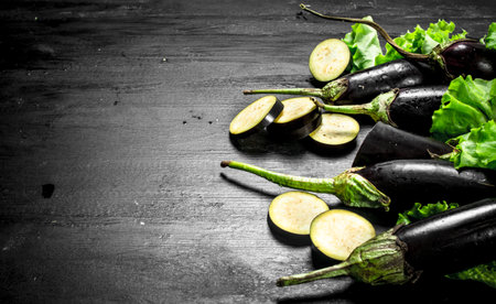 Fresh eggplant and sliced pieces. On the black chalkboard.の写真素材