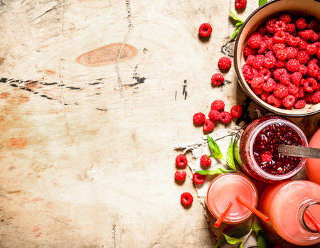 The juice of fresh raspberries and jam. On a wooden table.の写真素材