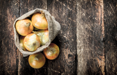 Fresh onions in an old bag. On a wooden background.の写真素材
