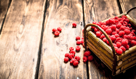Wild raspberries in the basket. On a wooden table.