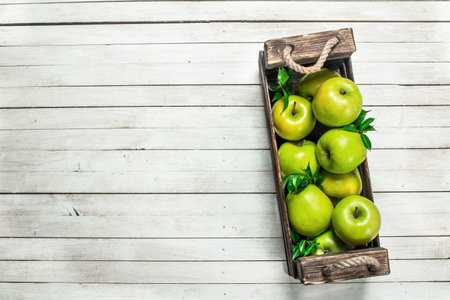 Green apples in a box. On a white wooden background.の写真素材