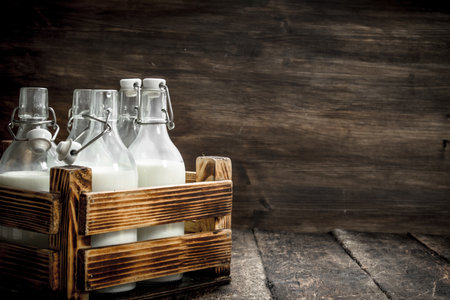 Bottles with fresh milk in a box. On a wooden background.の写真素材