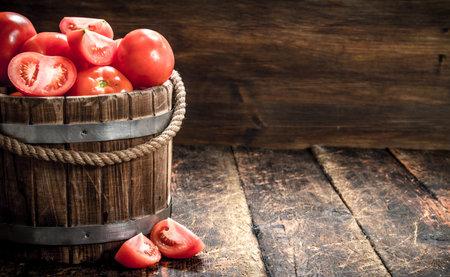 Fresh tomatoes in a wooden bucket. On a wooden background.の写真素材