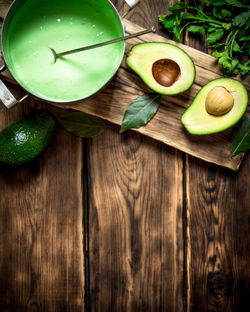 The guacamole and greens on the Board. On wooden background.の写真素材