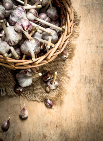 Garlic in an old basket. On a wooden background.の写真素材