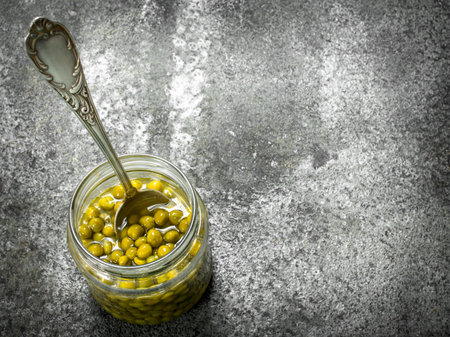 Marinated green peas in glass jar. On a rustic background.の写真素材