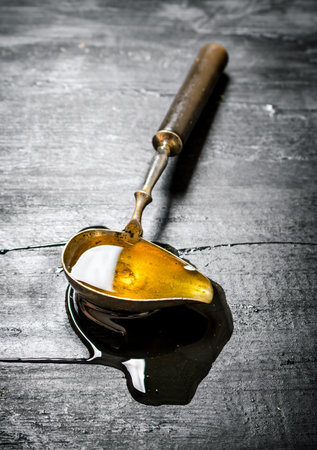 Vintage spoon with natural honey . On black rustic table.の写真素材