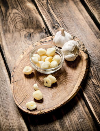 Peeled cloves of garlic on a wooden trunk. On wooden background.の写真素材