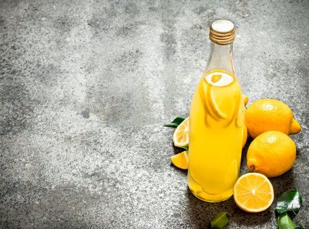 Lemonade in the bottle with slices of fresh lemons. On rustic background.の写真素材
