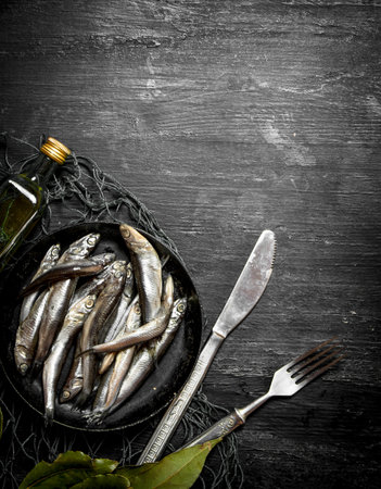 Sprat Bay leaf in a fishing net. On a black wooden background.の写真素材