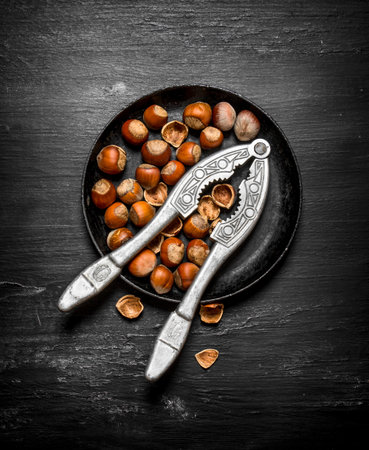 Hazelnuts with Nutcracker on the old plate. On the black wooden table.の写真素材