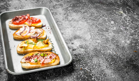 Various sandwiches with red caviar, bacon, cheese and fresh vegetables on a steel tray. On a rustic background.の写真素材