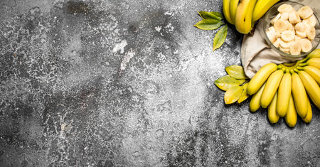 Fresh bananas with pieces of sliced bananas in a bowl. On rustic background.の写真素材