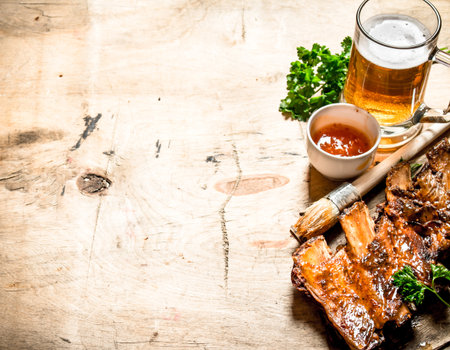 Barbecue pork ribs with tomato sauce and beer. On wooden background.の写真素材