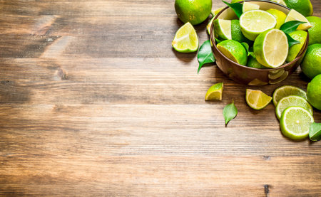 Ripe limes in a bowl. On a wooden table.の写真素材