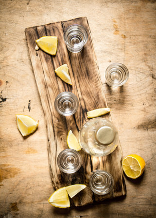 Bottle of vodka with shot glasses and lemon. On wooden background.の写真素材