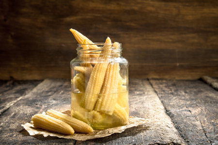 Pickled corn in glass jar. On a wooden background.の写真素材