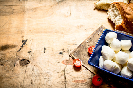 Mozzarella with fresh bread and tomatoes. On a wooden table.の写真素材