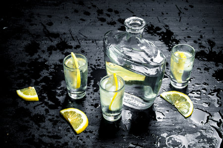 Vodka in glasses with lemon and ice. On the black chalkboard.の写真素材