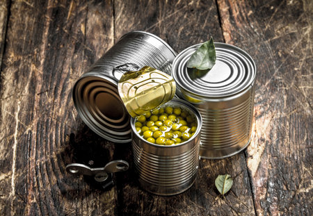 Canned green peas in a tin can with opener. On a wooden background.の写真素材