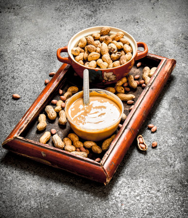 Nuts and peanut butter in a bowl. On rustic background.