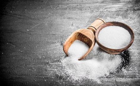 Salt in a wooden bowl. On the black chalkboard.の写真素材