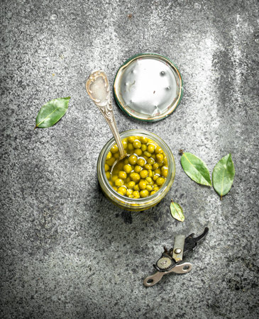 Marinated green peas in glass jar. On a rustic background.の写真素材