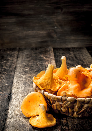 Mushrooms chanterelle in the basket. On a wooden background.の写真素材