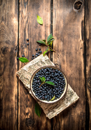 Wild blueberries in a Cup on the stand. On a wooden table.の写真素材