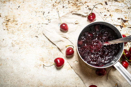 Cherry jam in a saucepan on the old fabric. On rustic background.の写真素材