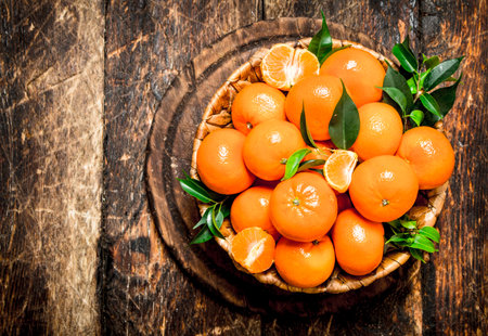 Fresh tangerines in the basket. On wooden background.の写真素材